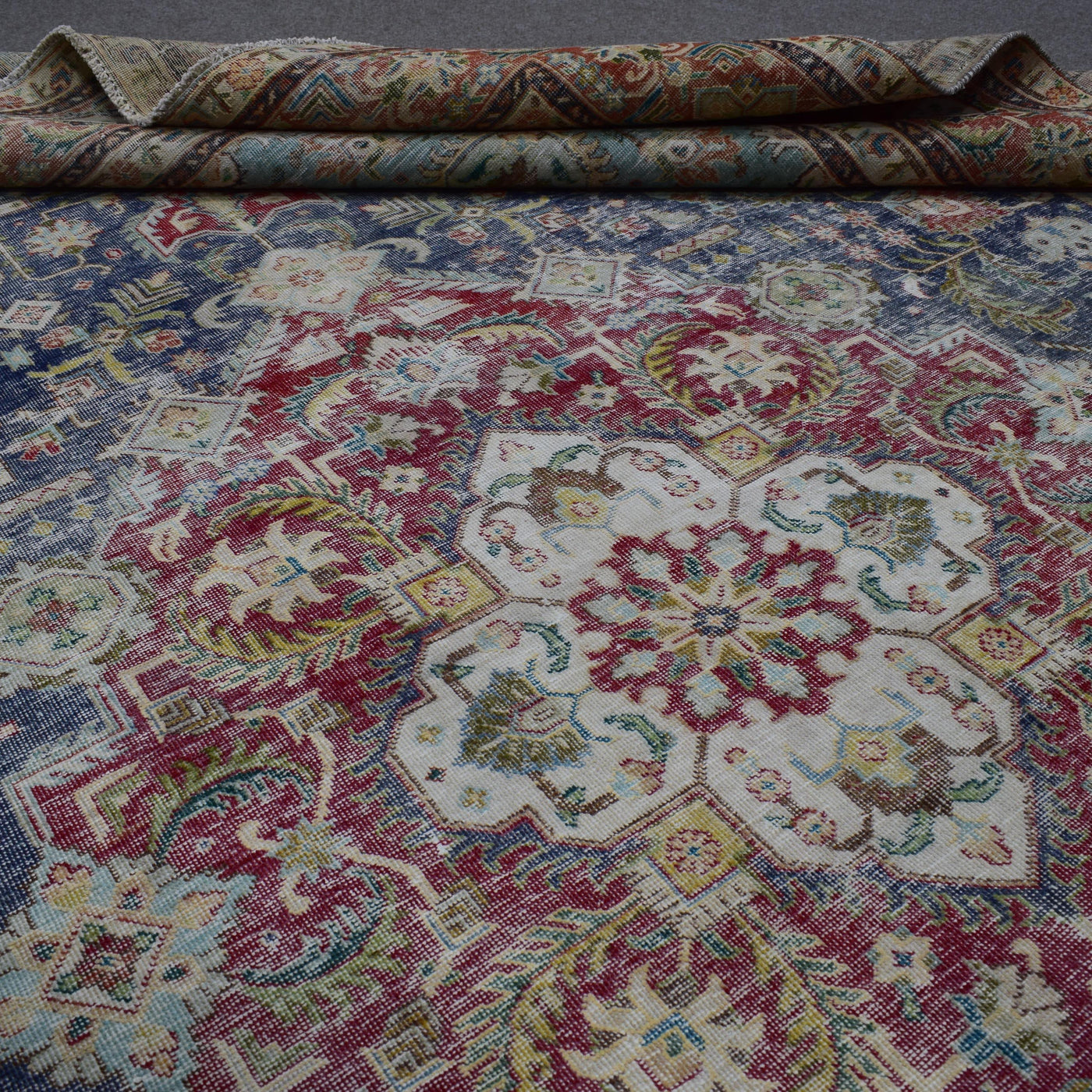 Detailed view of distressed Persian rug pattern with faded navy background and ornamental motifs