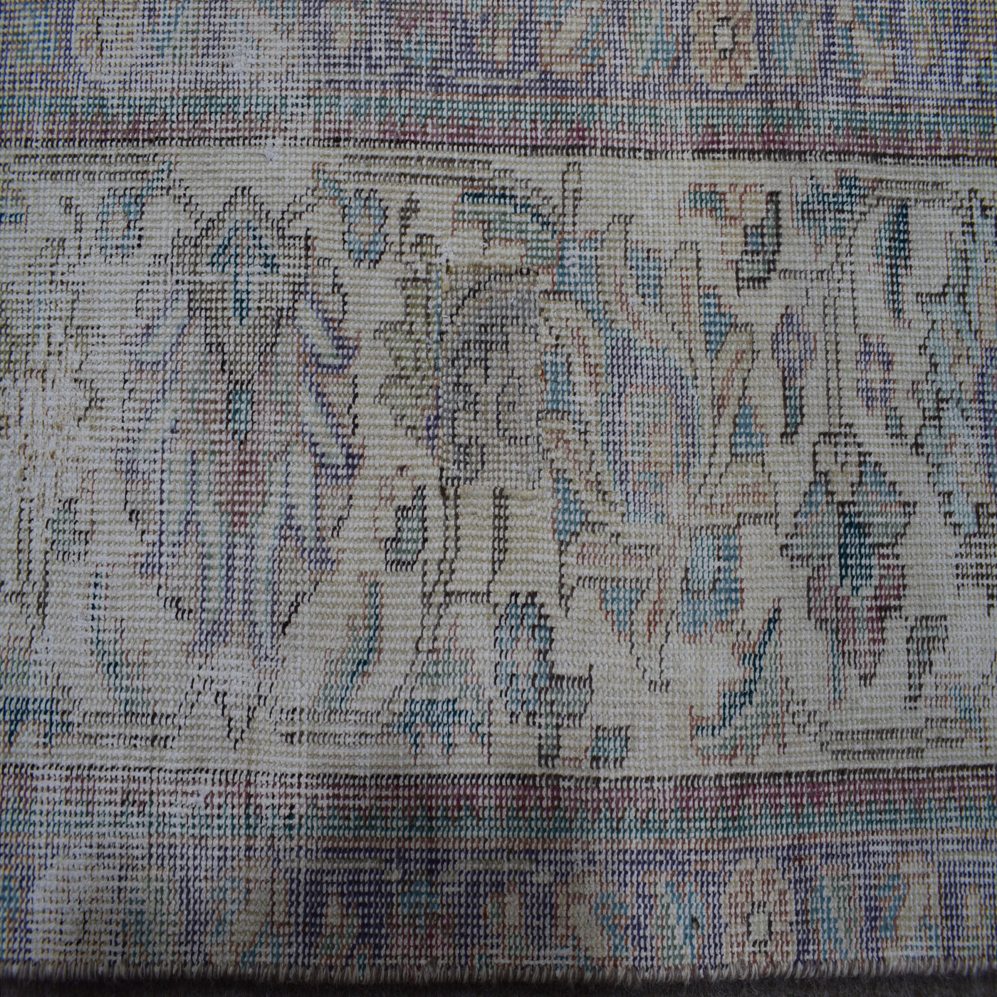 Close up of Persian rug border with intricate floral motifs and subtle guard stripes