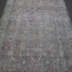 Close up of distressed Persian rug showing faded floral motifs on ivory background
