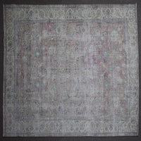 Hand knotted Persian rug photographed at an angle showing overall distressed pattern and neutral color palette