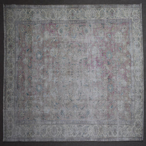 Hand knotted Persian rug photographed at an angle showing overall distressed pattern and neutral color palette