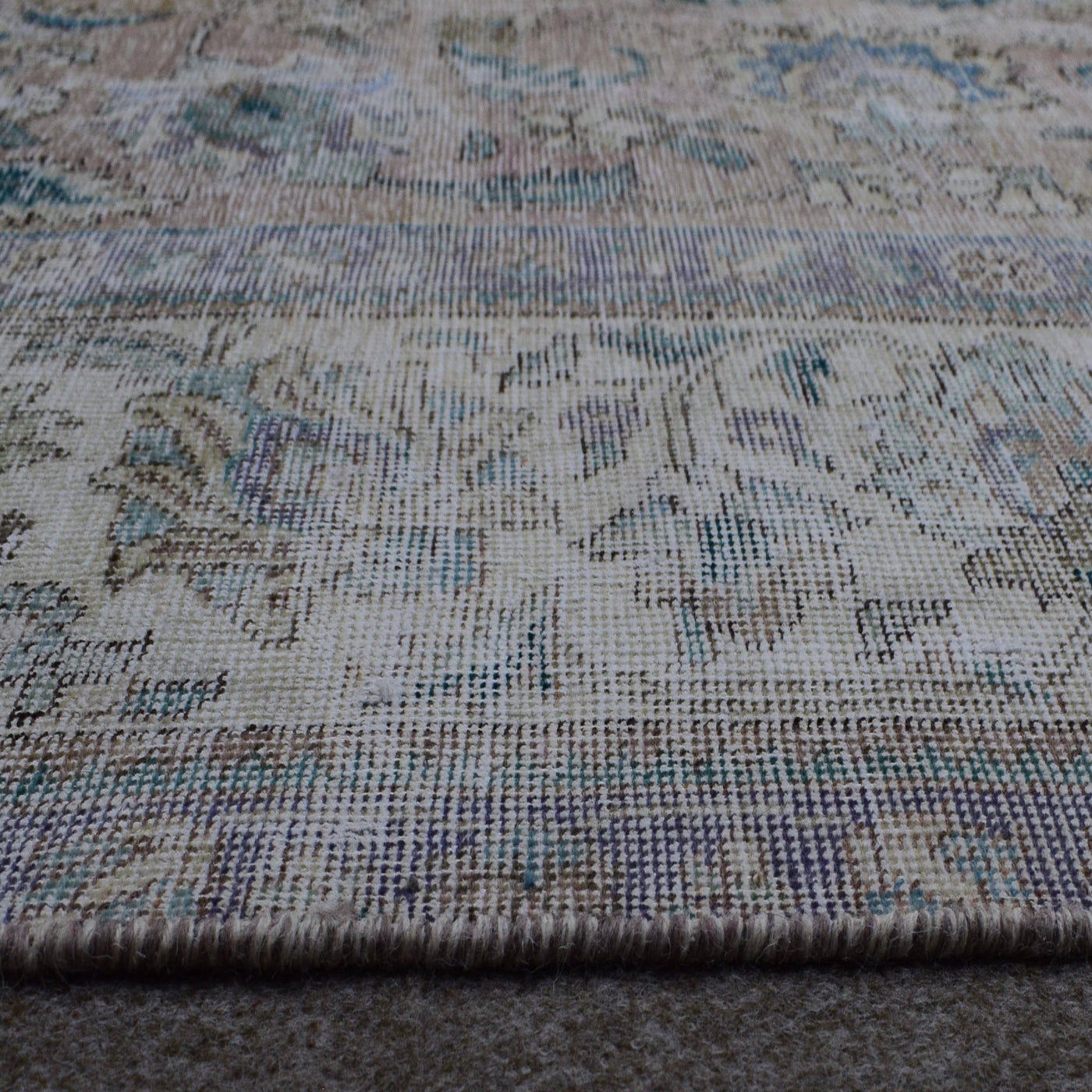 Macro close up of Persian rug pile showing worn wool texture and faded vintage surface