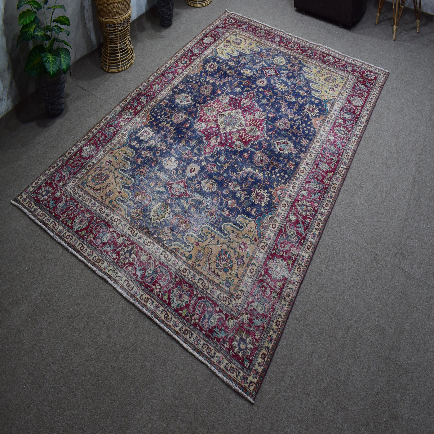 Hand knotted Persian rug photographed at an angle showing overall medallion layout and distressed navy tones