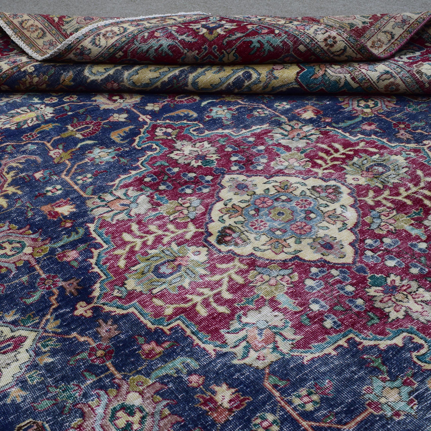 Detailed view of distressed Persian rug pattern with navy background and ornamental motifs