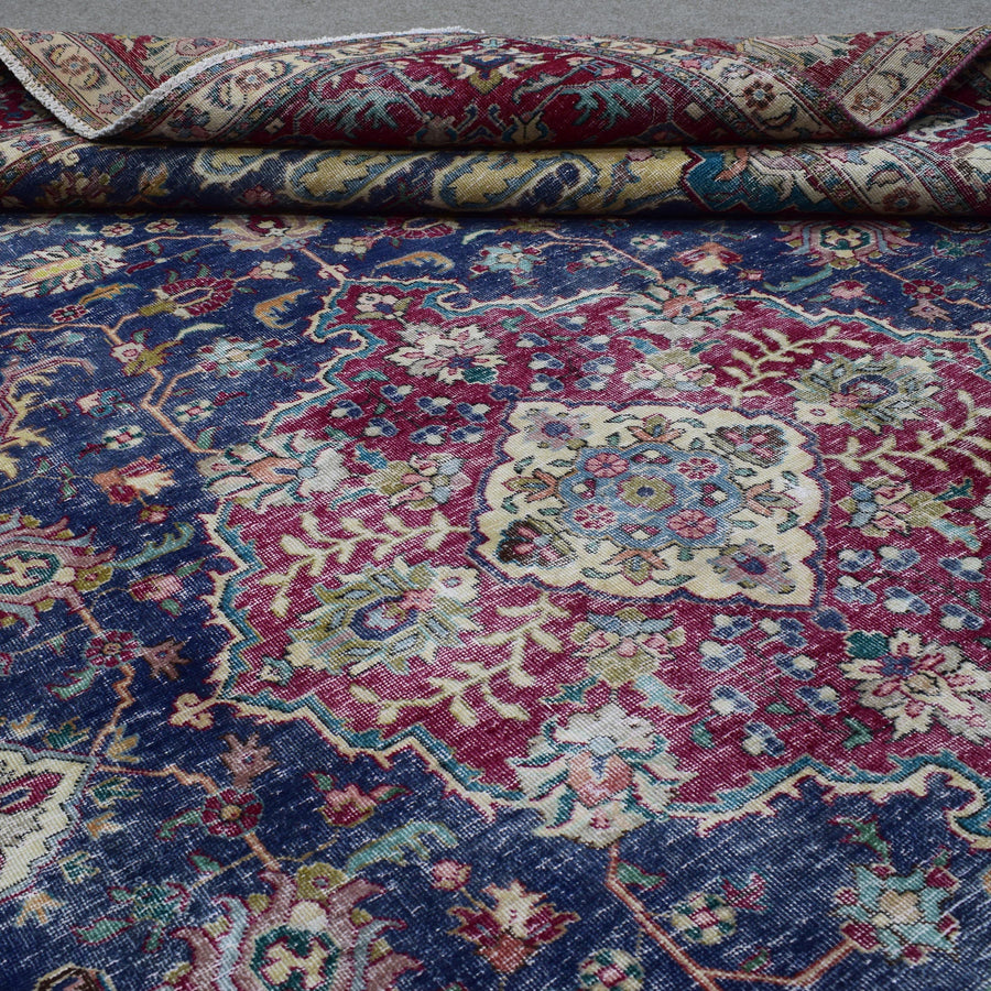Detailed view of distressed Persian rug pattern with navy background and ornamental motifs