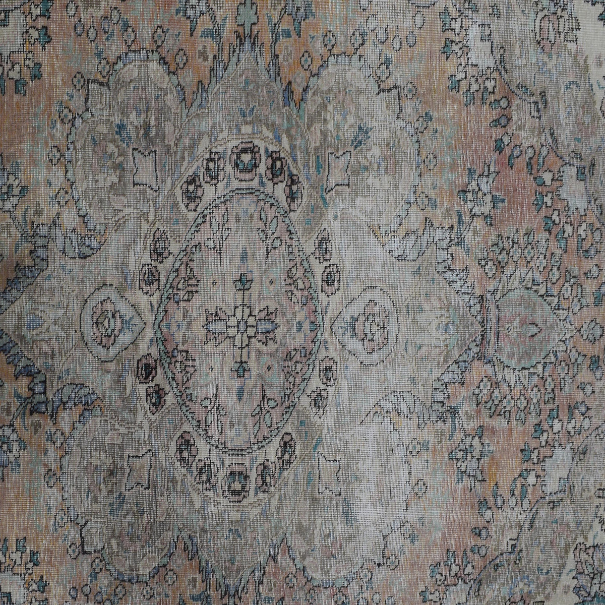 Detailed view of vintage Persian rug pattern featuring traditional floral medallion on faded ivory background
