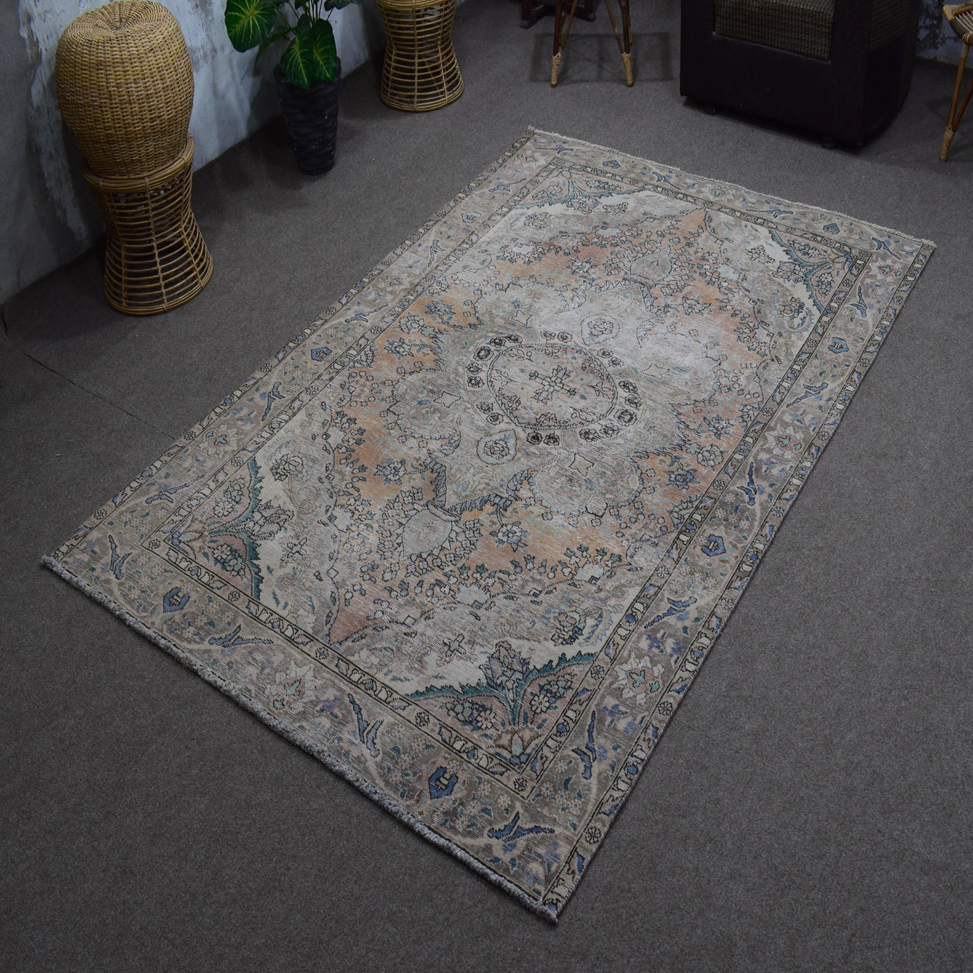 Hand knotted Persian rug photographed at an angle showing overall medallion layout and distressed neutral palette