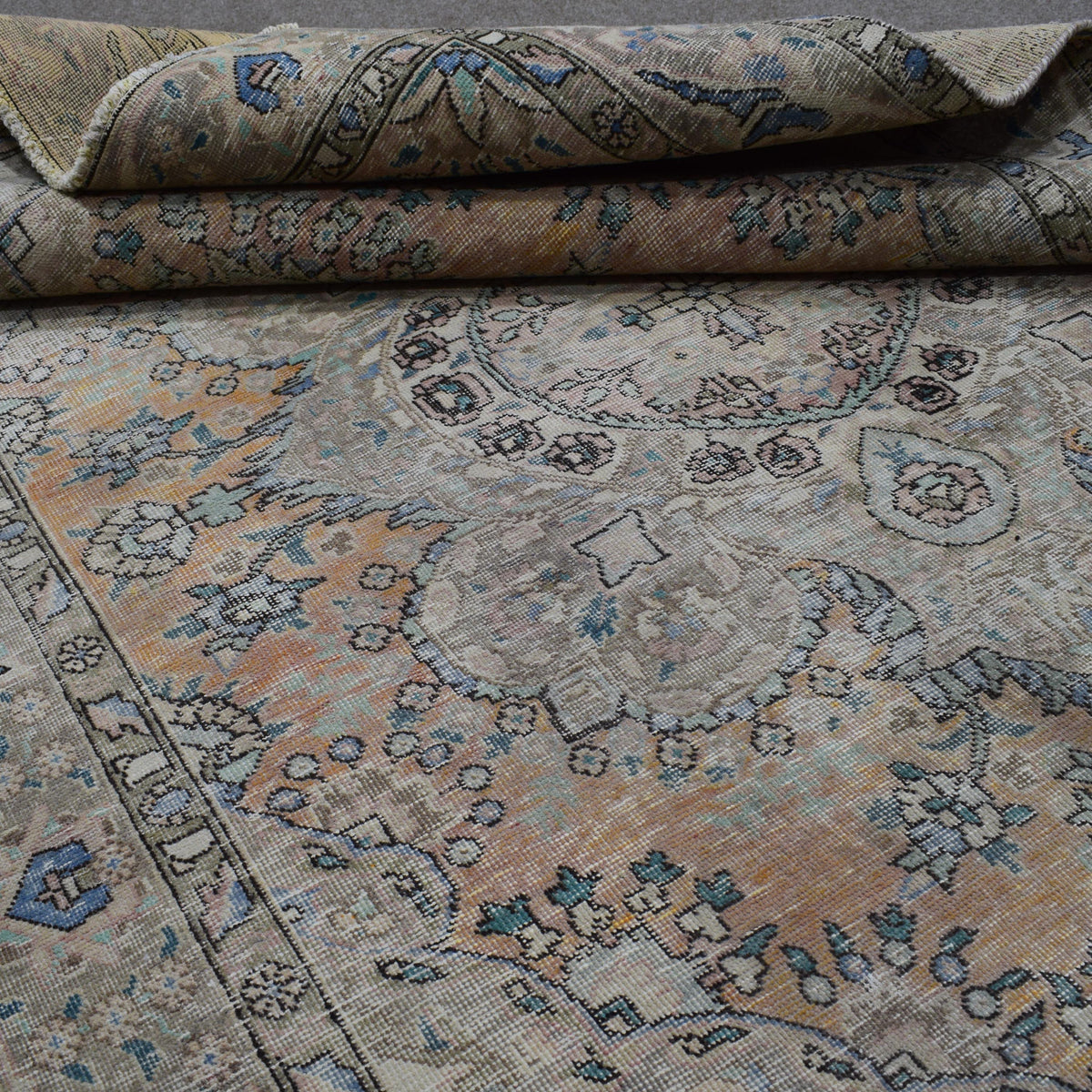 Detailed view of distressed Persian rug pattern with faded ivory field and ornamental motifs