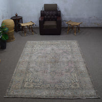 Small distressed vintage Persian rug 198x285 cm styled in interior showing soft neutral tones and worn floral pattern