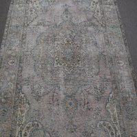 Close up of distressed Persian rug showing faded medallion with delicate floral motifs