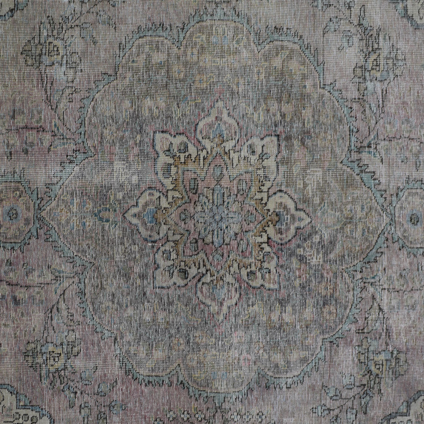 Detailed view of vintage Persian rug pattern featuring intricate floral medallion on faded ivory background