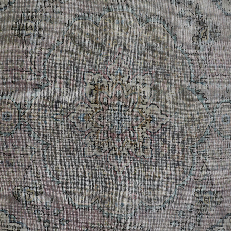 Detailed view of vintage Persian rug pattern featuring intricate floral medallion on faded ivory background