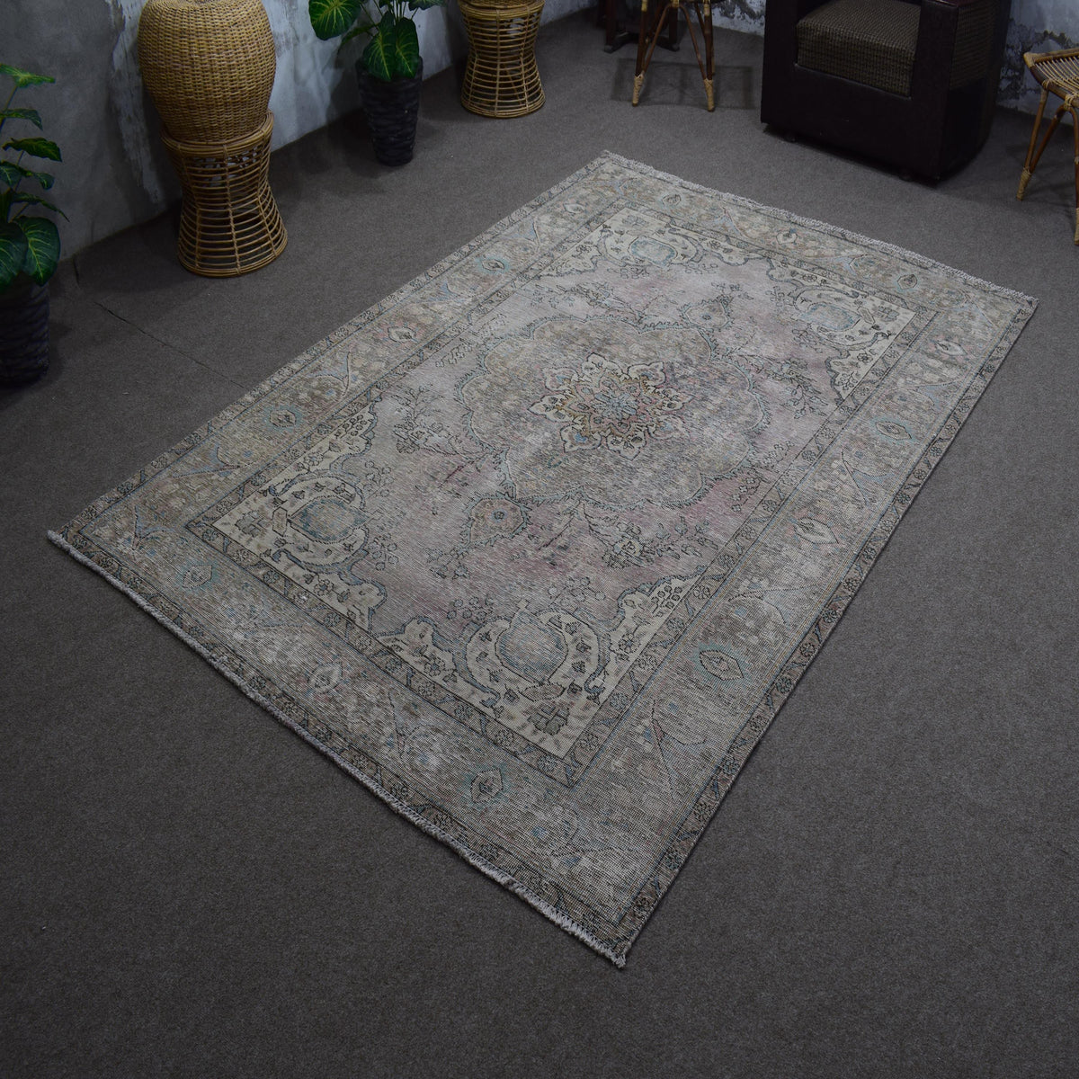 Hand knotted Persian rug photographed at an angle showing overall distressed pattern and neutral palette