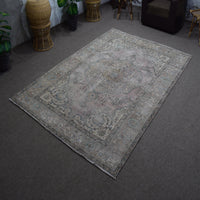 Hand knotted Persian rug photographed at an angle showing overall distressed pattern and neutral palette