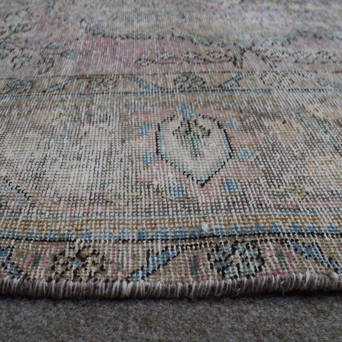 Macro detail of Persian rug medallion highlighting worn wool texture and faded pattern