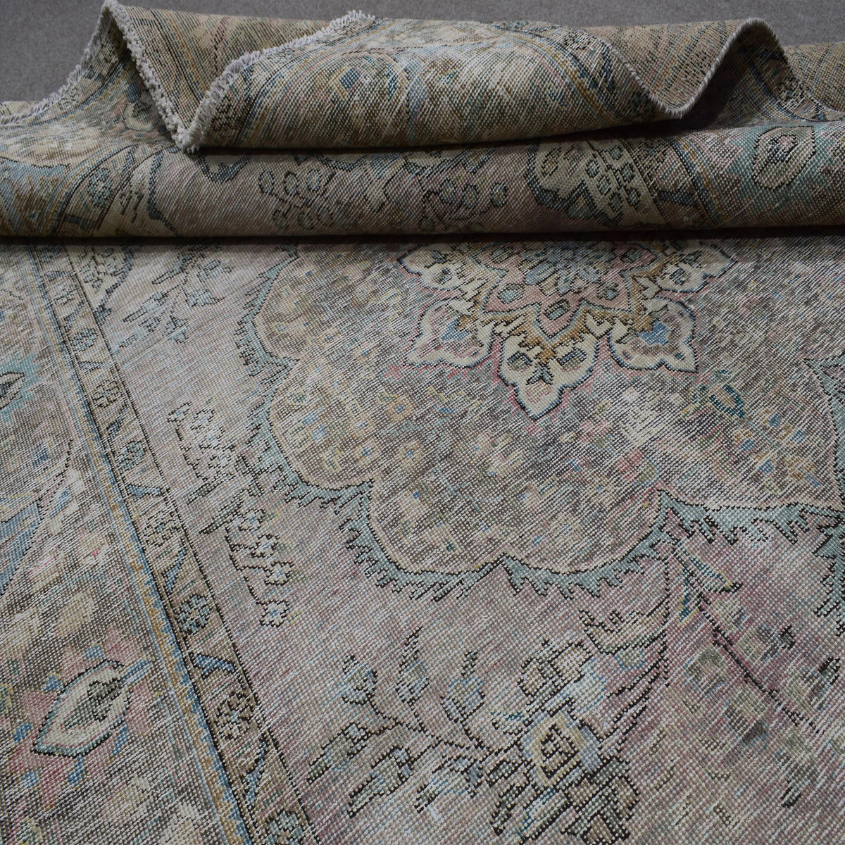 Detailed view of distressed Persian rug pattern with muted ivory tones and ornamental motifs