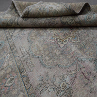 Detailed view of distressed Persian rug pattern with muted ivory tones and ornamental motifs
