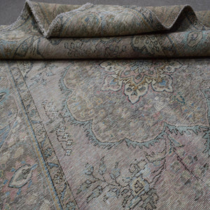 Detailed view of distressed Persian rug pattern with muted ivory tones and ornamental motifs