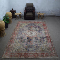 Large distressed vintage Persian rug 237x355 cm styled in interior showing navy background and classic medallion design