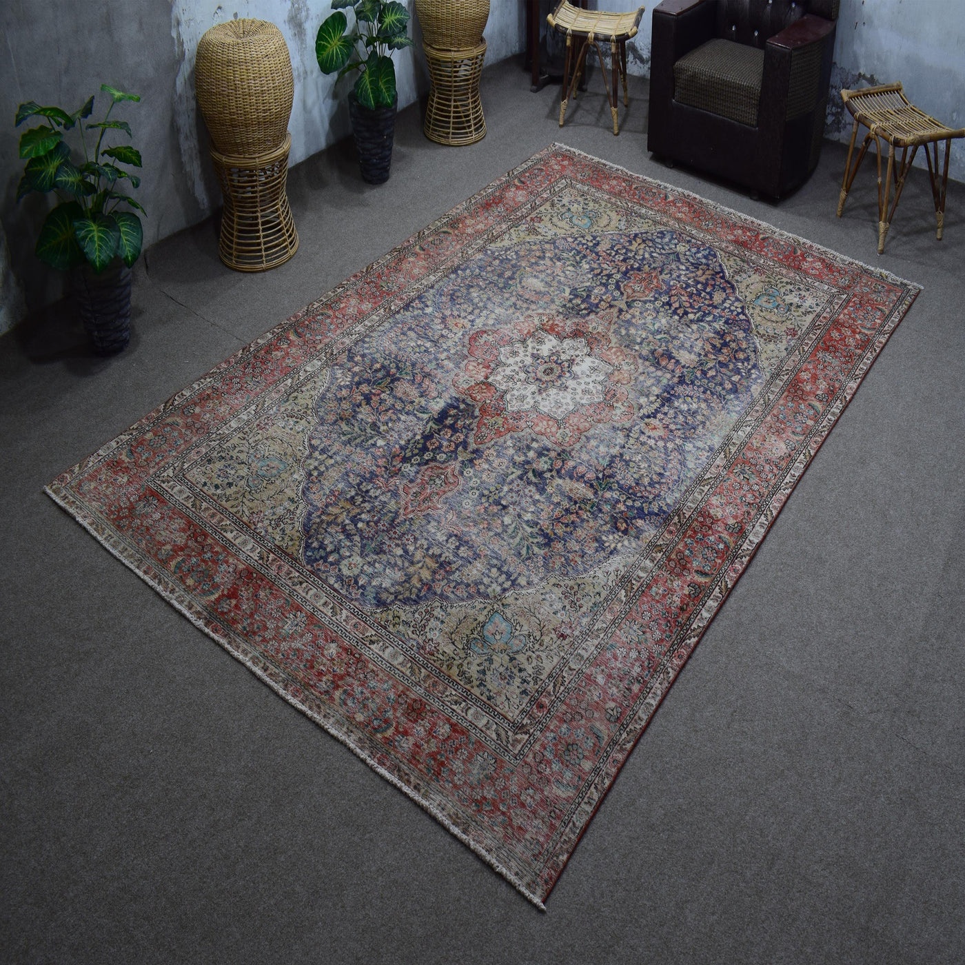 Hand knotted Persian rug photographed at an angle showing overall medallion layout and distressed navy tones