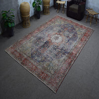 Hand knotted Persian rug photographed at an angle showing overall medallion layout and distressed navy tones