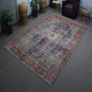 Hand knotted Persian rug photographed at an angle showing overall medallion layout and distressed navy tones
