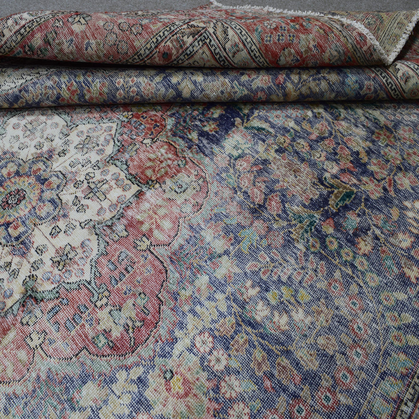 Detailed view of distressed Persian rug pattern with navy background and ornamental motifs
