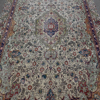 Close up of distressed Persian rug showing ornate medallion with colorful floral motifs