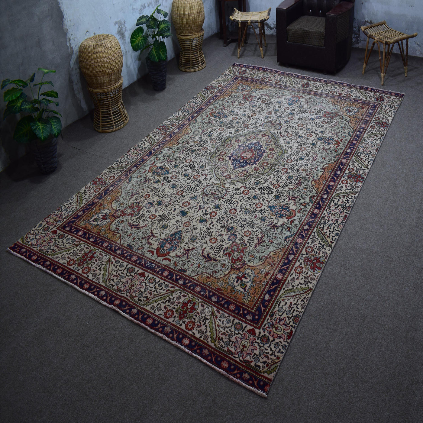Hand knotted Persian rug photographed at an angle showing overall medallion layout and distressed ivory palette