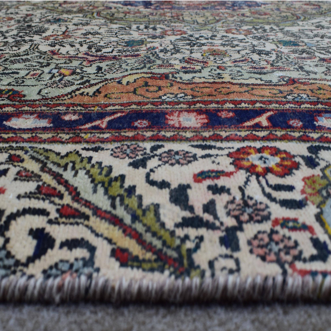 Close up of Persian rug border with vibrant floral motifs and intricate guard stripes