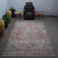 Vintage Persian rug 235x324 cm styled in interior showing soft rose tones and worn medallion design