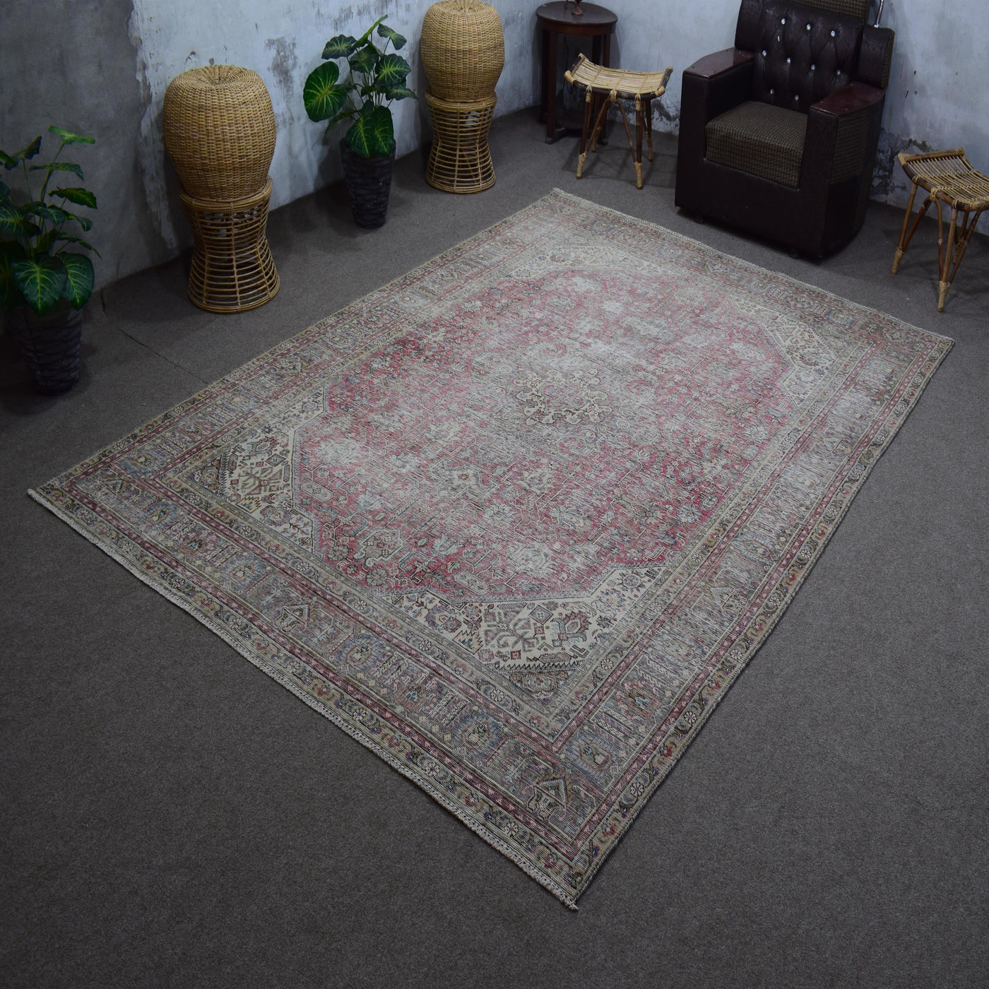 Hand knotted Persian rug photographed at an angle showing overall distressed pattern and vintage palette