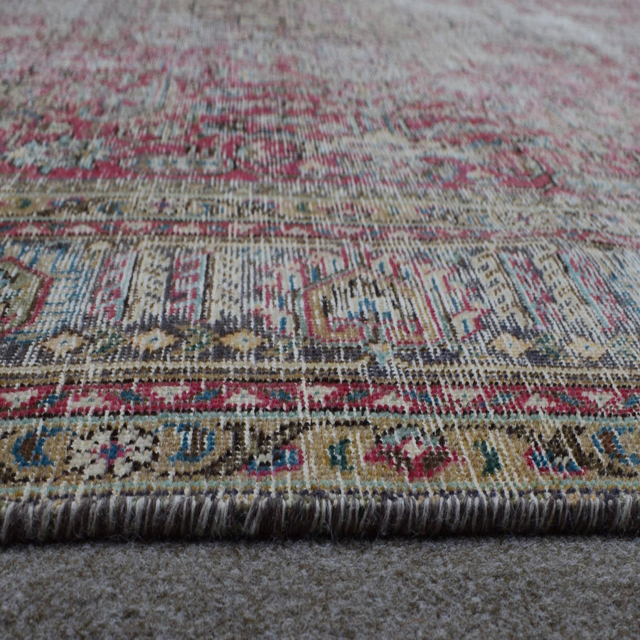 Macro detail of Persian rug pattern highlighting worn wool texture and faded design