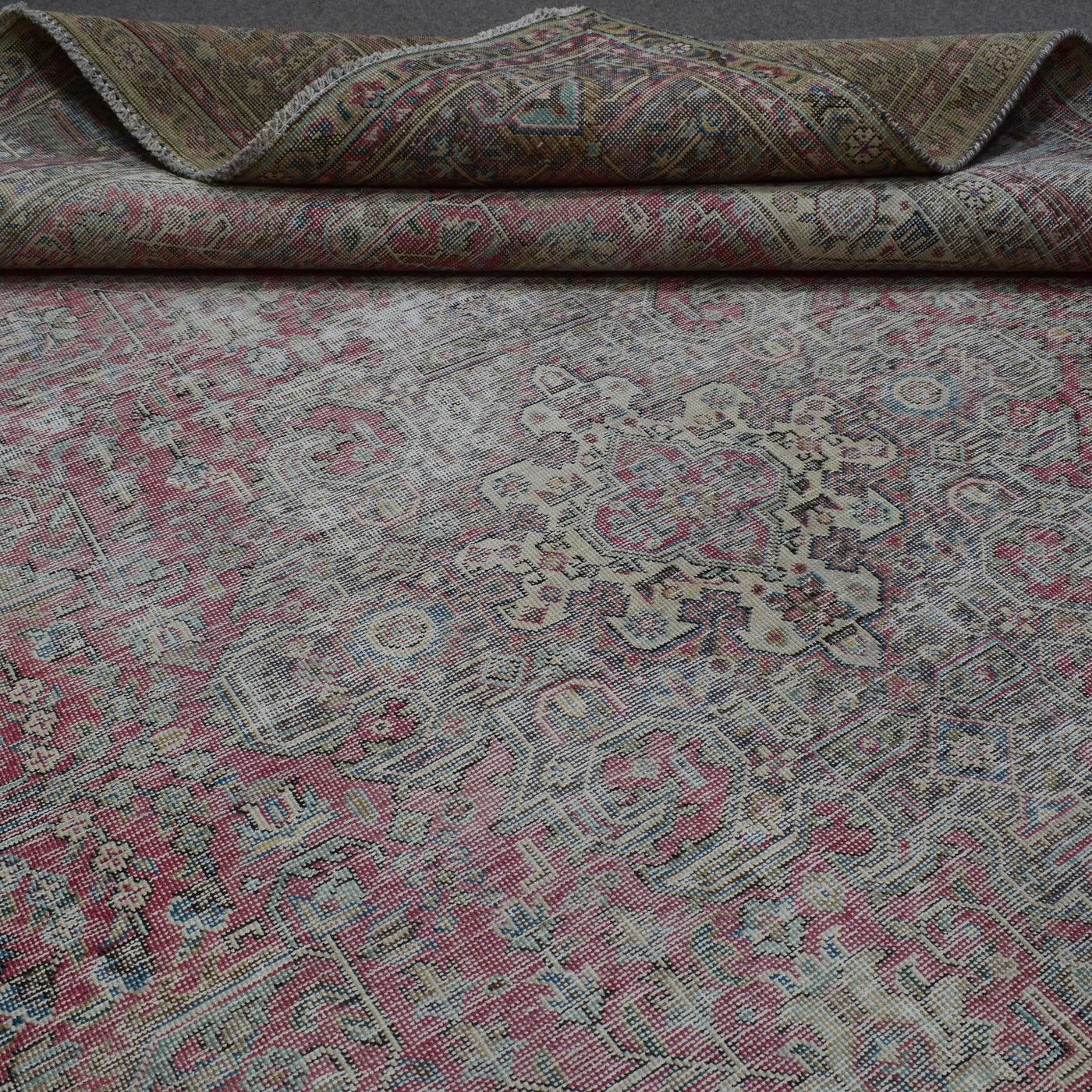 Detailed view of distressed Persian rug floral pattern with soft rose tones