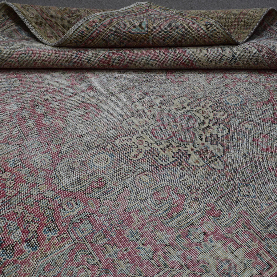Detailed view of distressed Persian rug floral pattern with soft rose tones