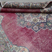 Detailed view of distressed Persian rug pattern with faded red field and ornamental motifs