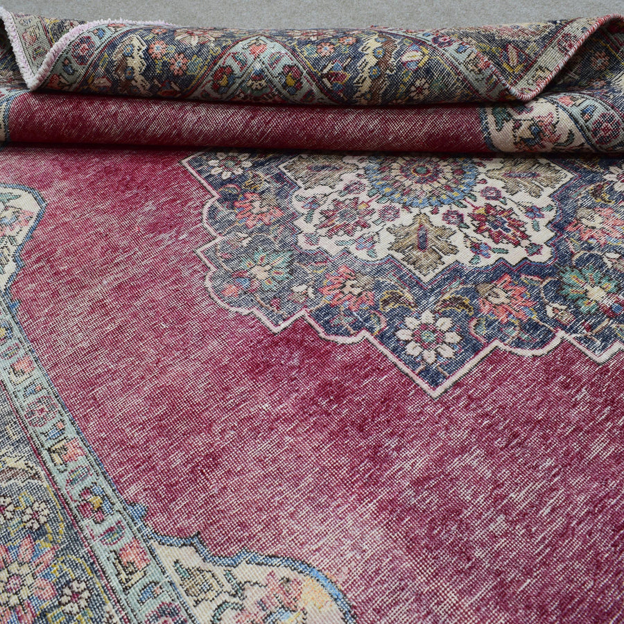Detailed view of distressed Persian rug pattern with faded red field and ornamental motifs