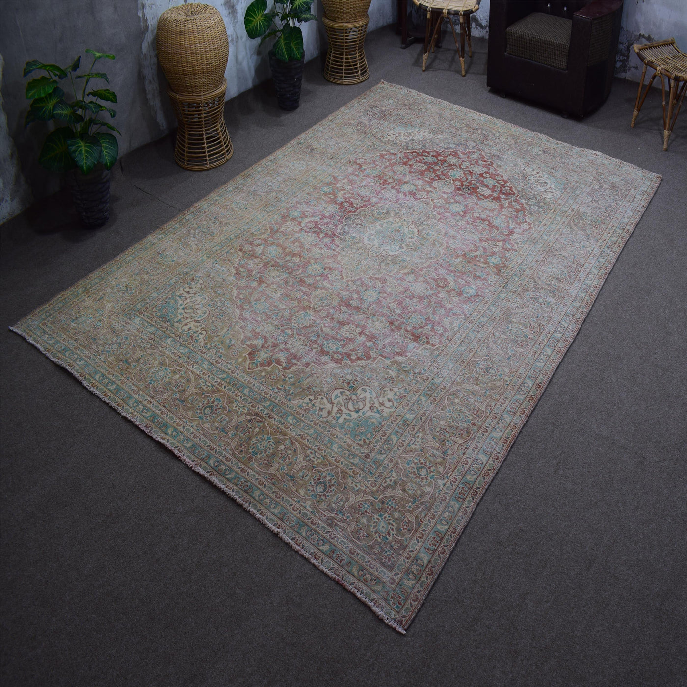 Hand knotted Persian rug photographed at an angle showing overall distressed pattern and neutral palette