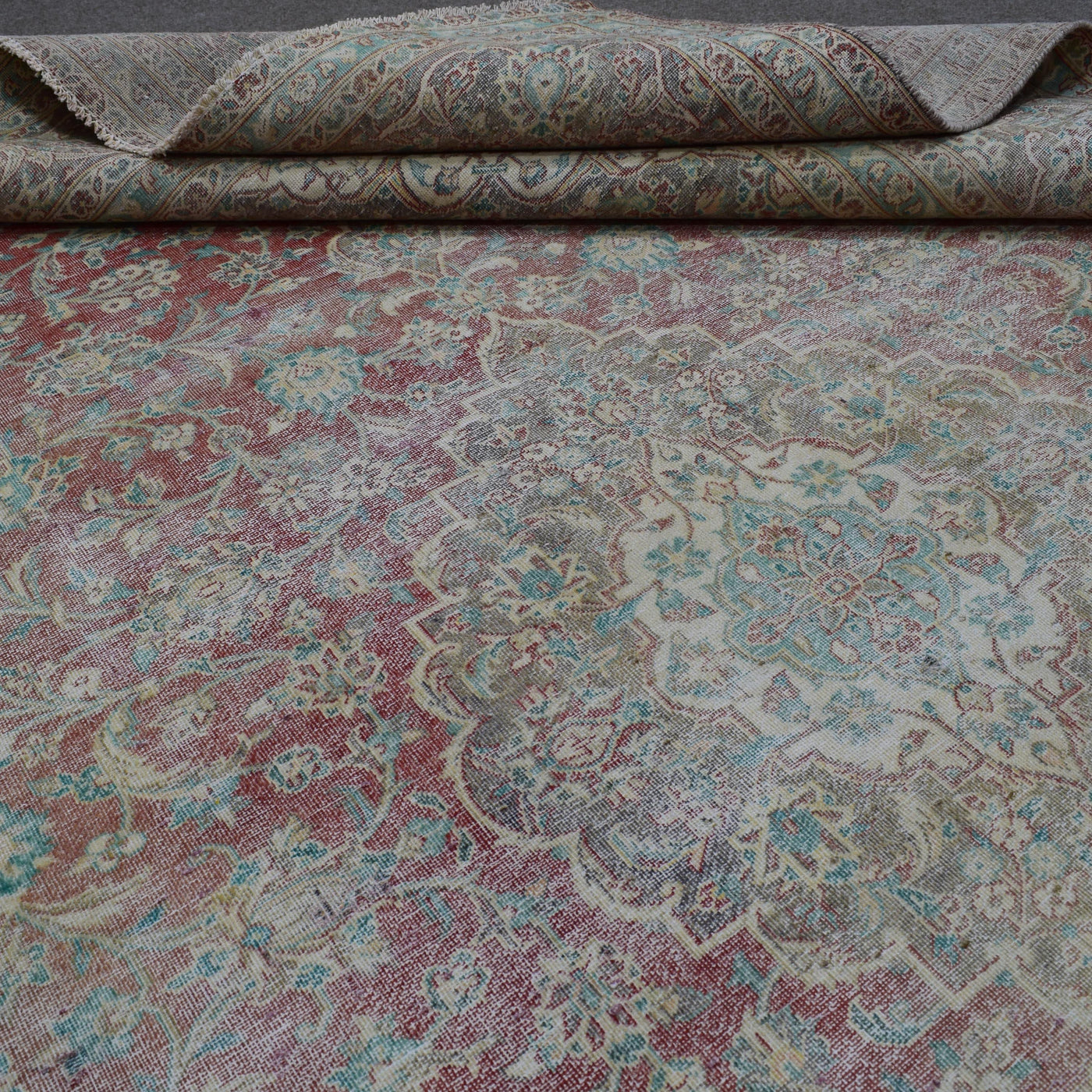 Detailed view of distressed Persian rug pattern with soft ivory tones and ornamental motifs