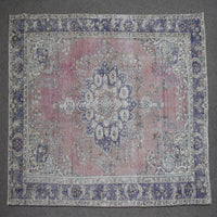 Hand knotted Persian rug photographed at an angle showing overall medallion layout and distressed rose tones