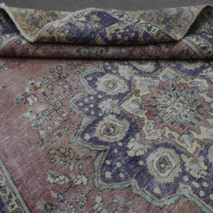 Detailed view of distressed Persian rug pattern with faded rose field and ornamental motifs