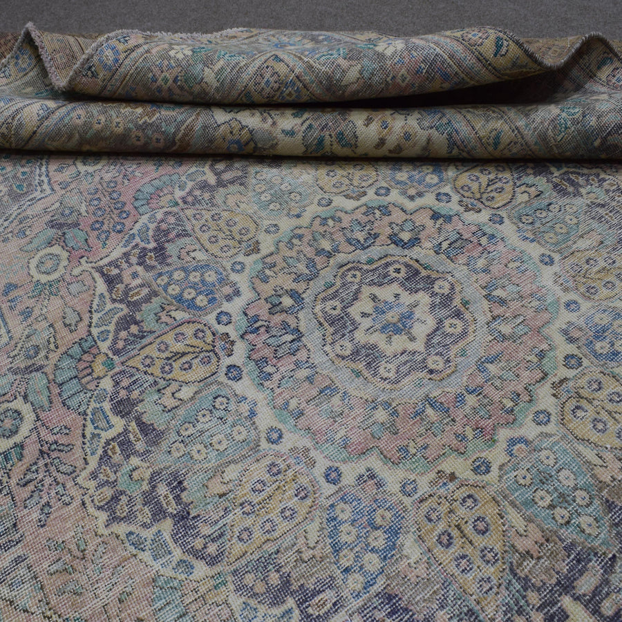 Detailed view of distressed Persian rug pattern with soft ivory tones and ornamental motifs