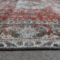 Hand knotted Persian rug photographed at an angle showing overall medallion layout and distressed vintage palette