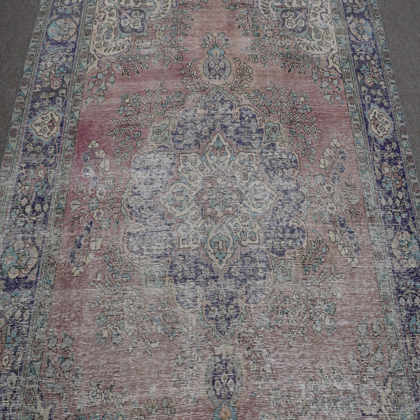 Close up of vintage Persian rug medallion with faded pink field and intricate floral motifs