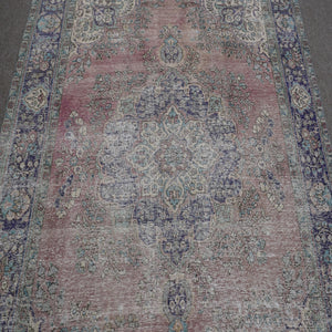 Close up of vintage Persian rug medallion with faded pink field and intricate floral motifs