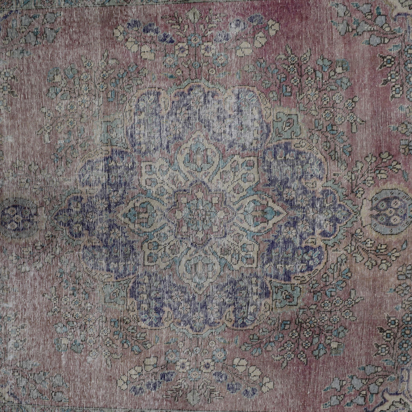 Detailed view of Persian rug center pattern with traditional floral medallion and distressed texture