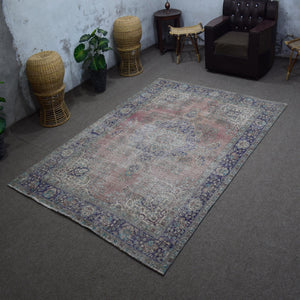 Angled view of hand knotted Persian rug highlighting full layout and worn vintage character