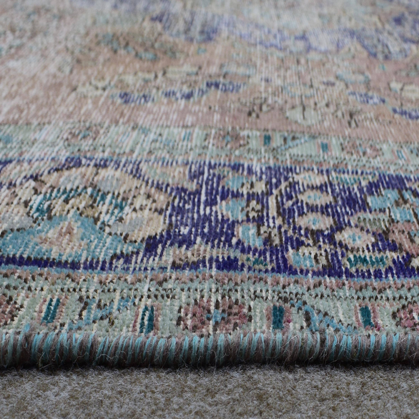 Macro detail of distressed Persian rug weaving showing worn wool texture and faded colors