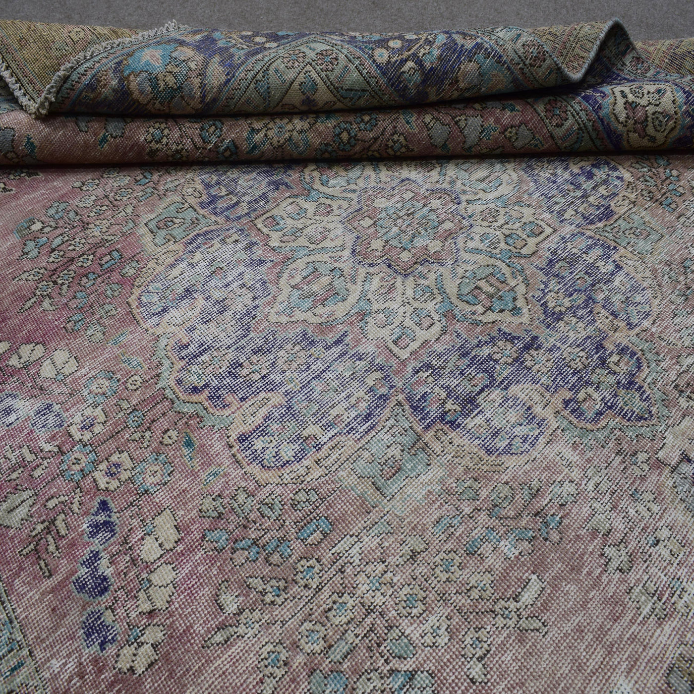 Close up of Persian rug medallion pattern with soft pastel tones and antique patina