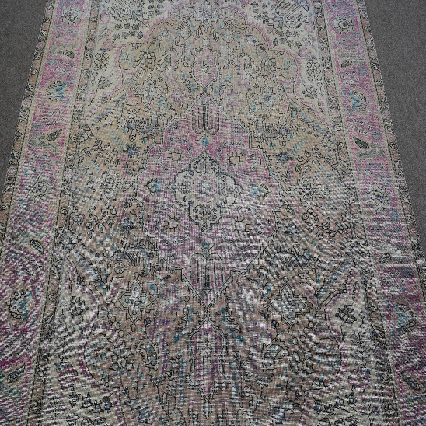 Close up of Persian rug medallion with faded pink and blue floral motifs